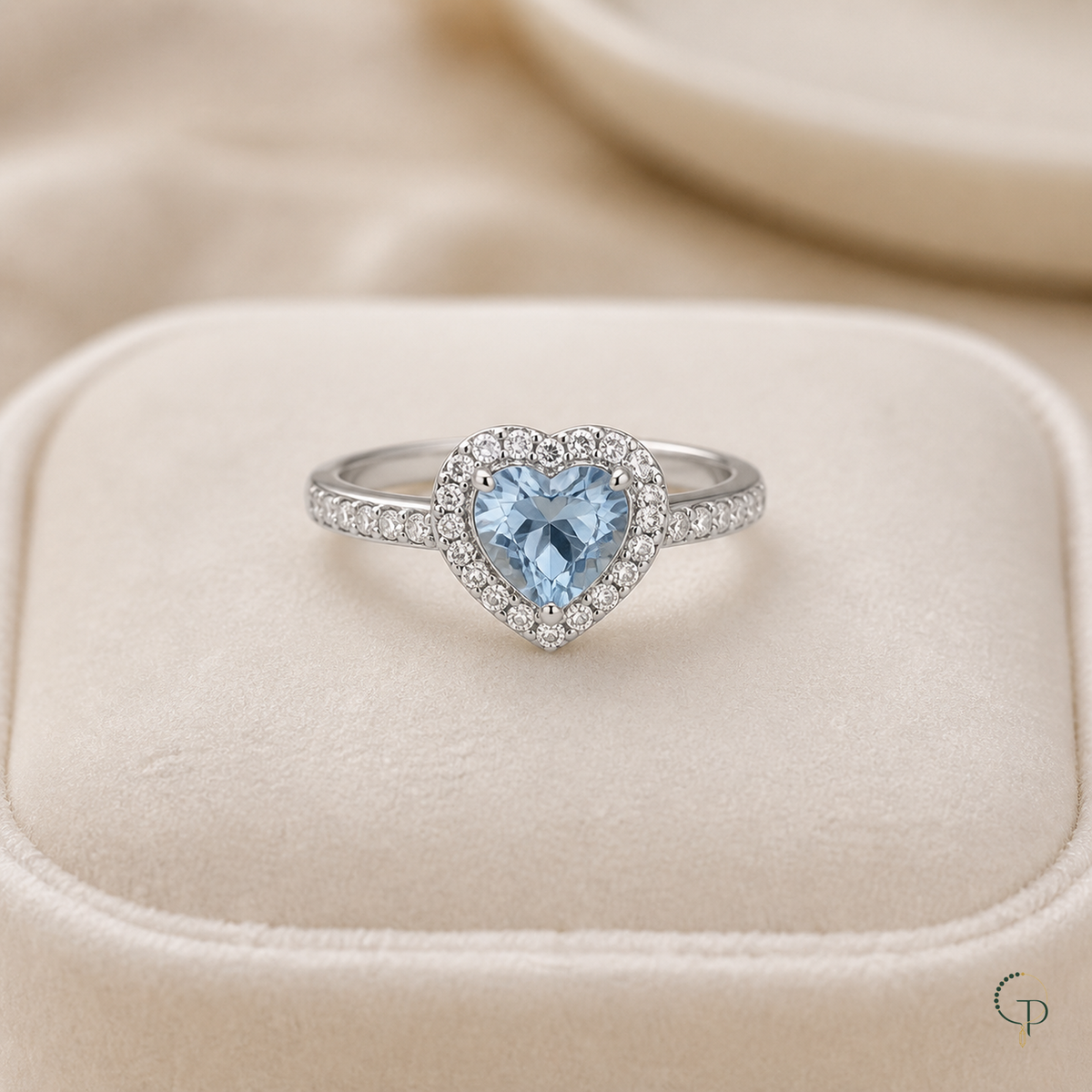 Silver-color blue heart halo ring displayed on an unbranded ivory jewelry cushion