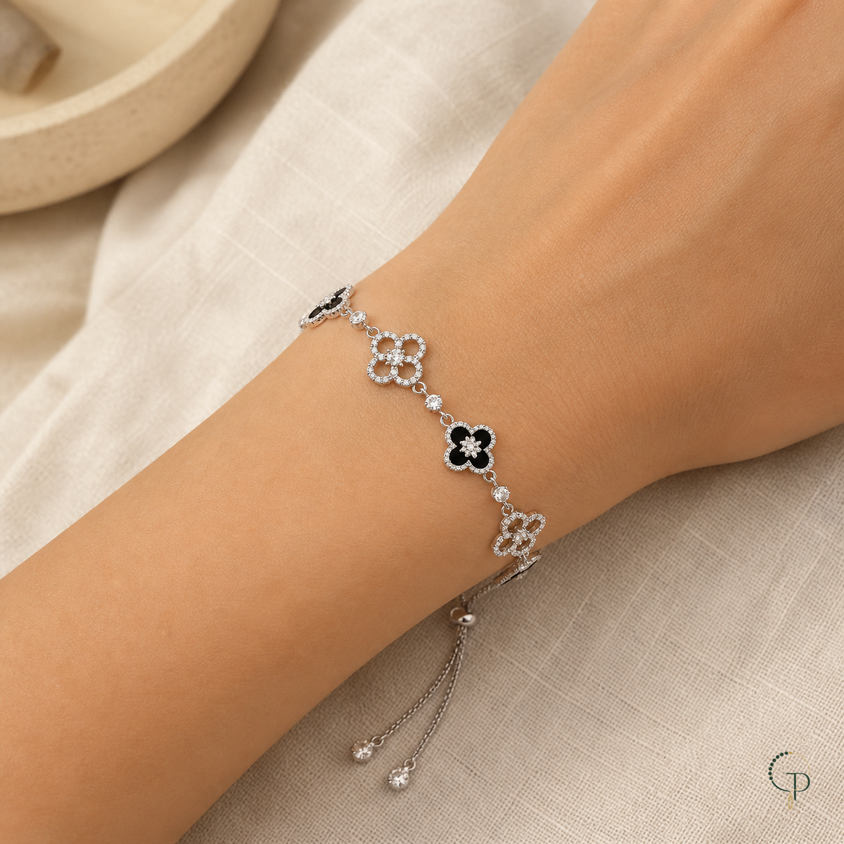 Black and clear-stone five-motif clover slider bracelet worn around a wrist