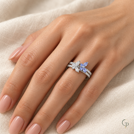 Double butterfly pavé-style ring worn on a hand beside ivory linen
