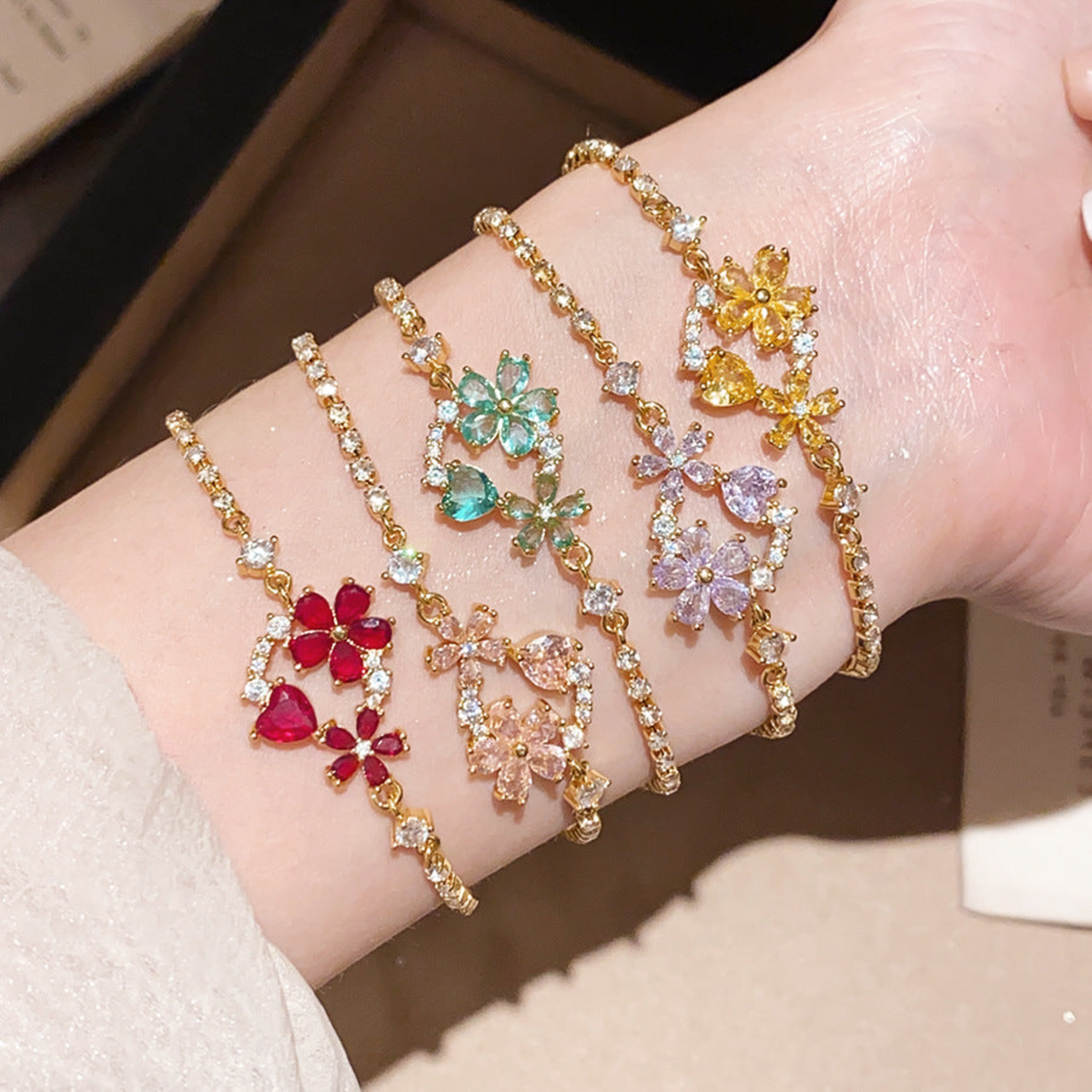Five colorful floral crystal tennis bracelets worn together on the wrist