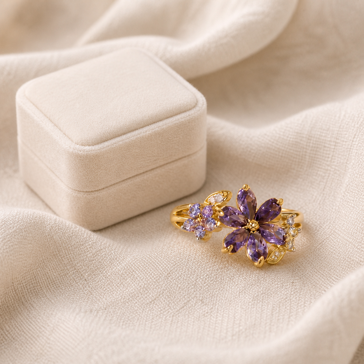 Purple marquise-stone floral ring styled beside an unbranded ivory ring box