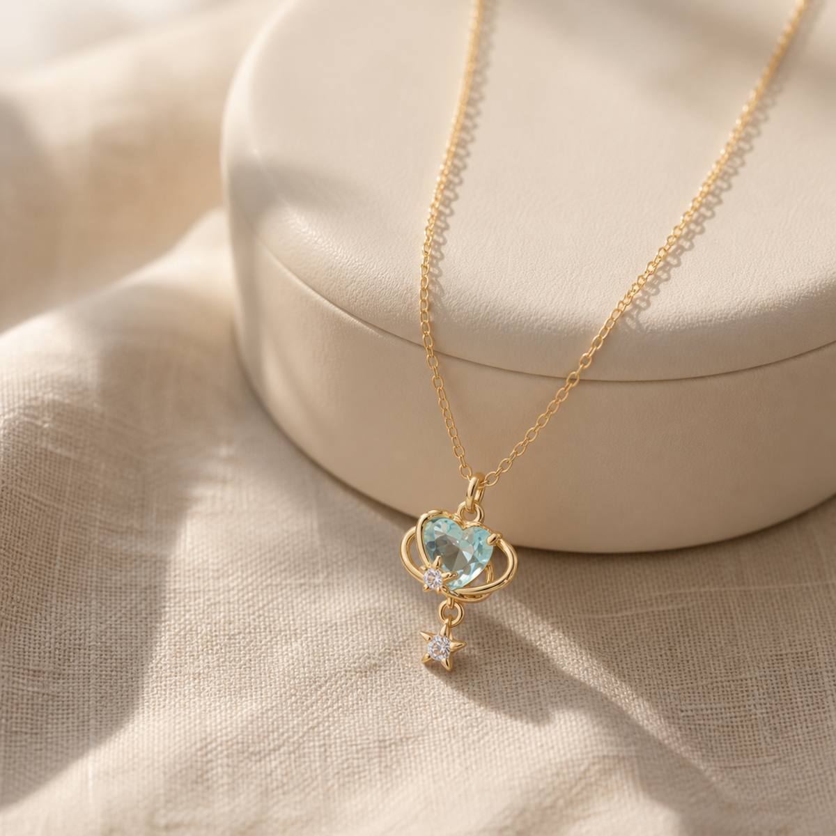 Aqua orbit star drop necklace on an ivory atelier display pedestal