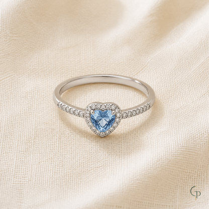 Complete silver-color blue heart halo ring arranged on warm ivory linen
