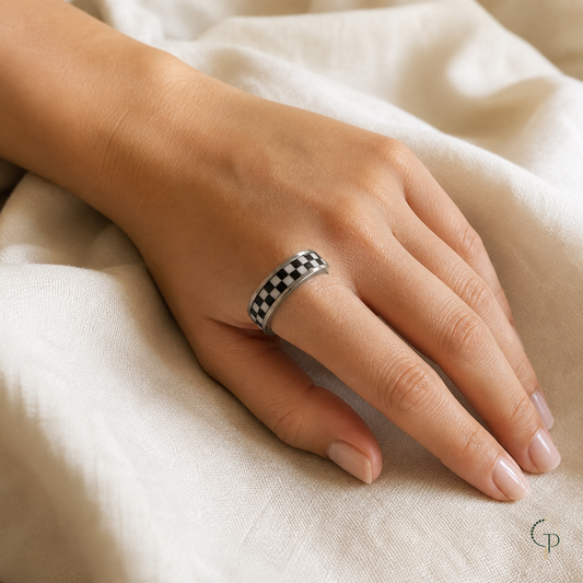 Silver-color checkerboard spinner ring worn on an anonymous hand over ivory linen