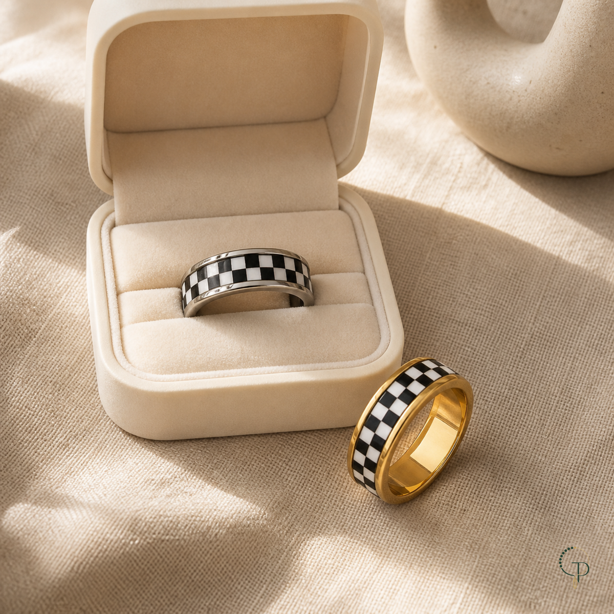 Silver-color and gold-color checkerboard rings styled with an unbranded ivory jewelry box