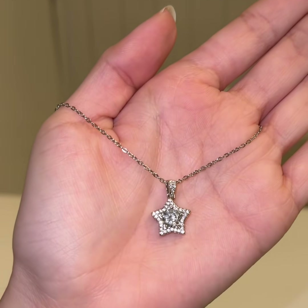 Source-video hand view showing the star pendant necklace for visual scale