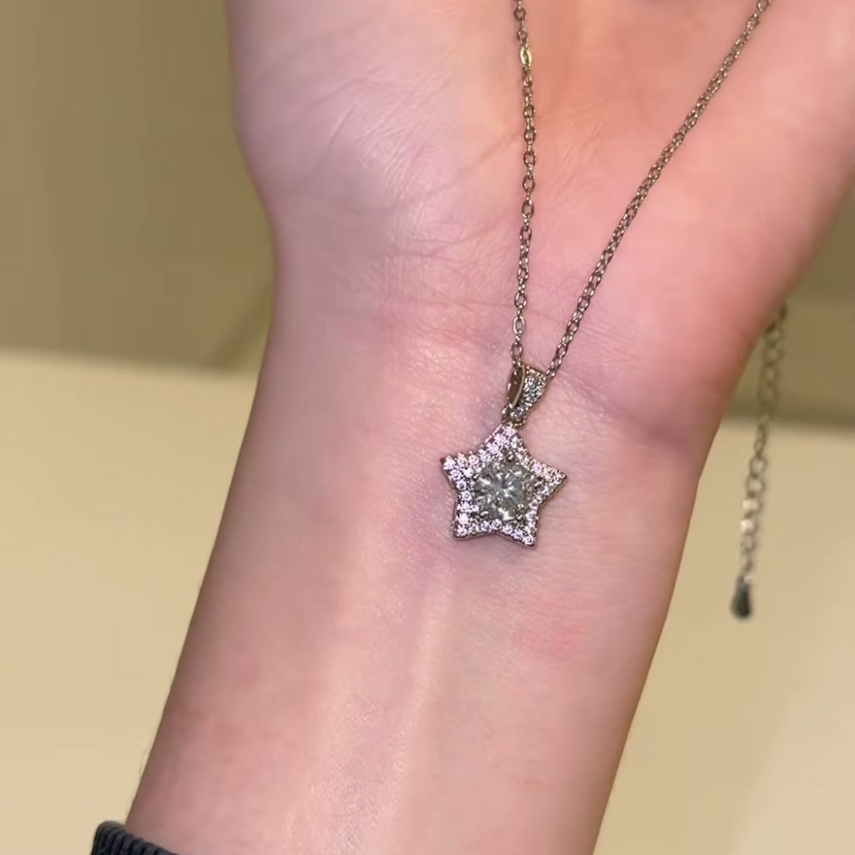 Source-video forearm view showing the star pendant, detailed bail and chain
