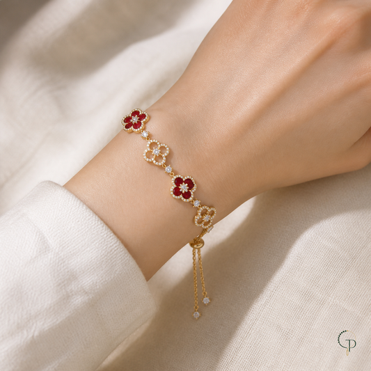 Red and clear-stone clover slider bracelet worn around a wrist on ivory linen