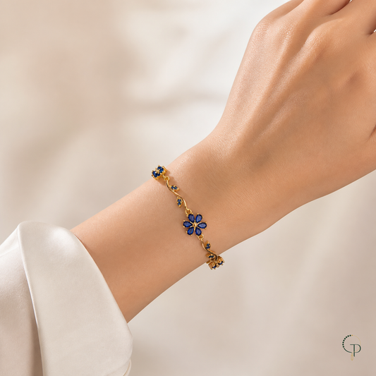 Gold-color vine bracelet with a blue flower centerpiece worn on the wrist