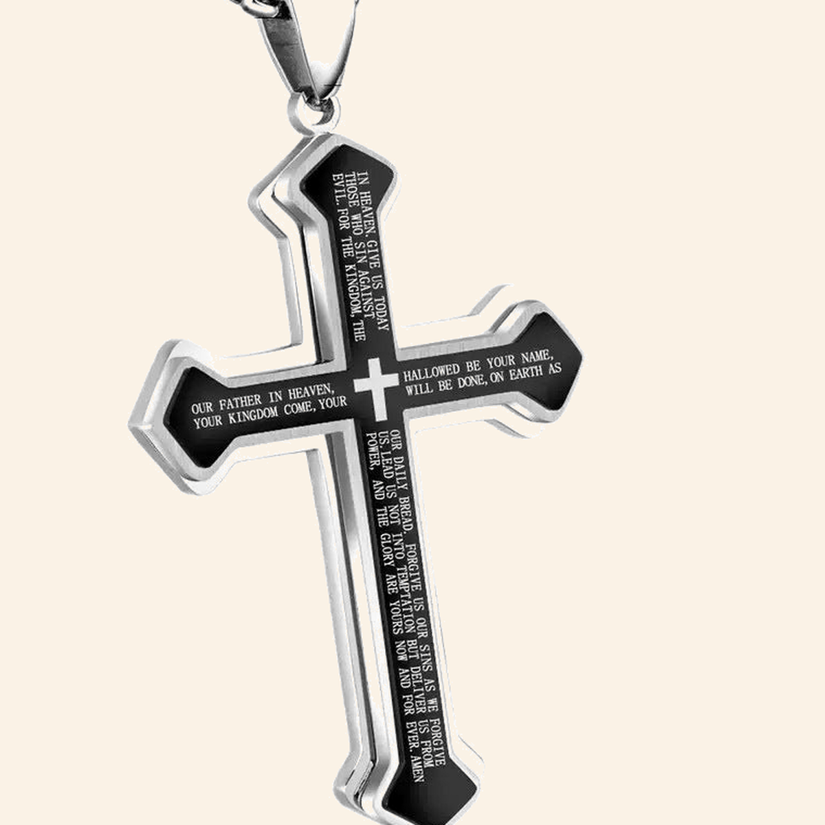 Close-up of engraved Our Father prayer text on cross pendant