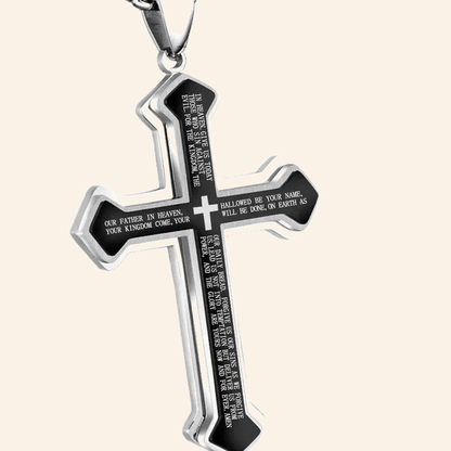 Close-up of engraved Our Father prayer text on cross pendant