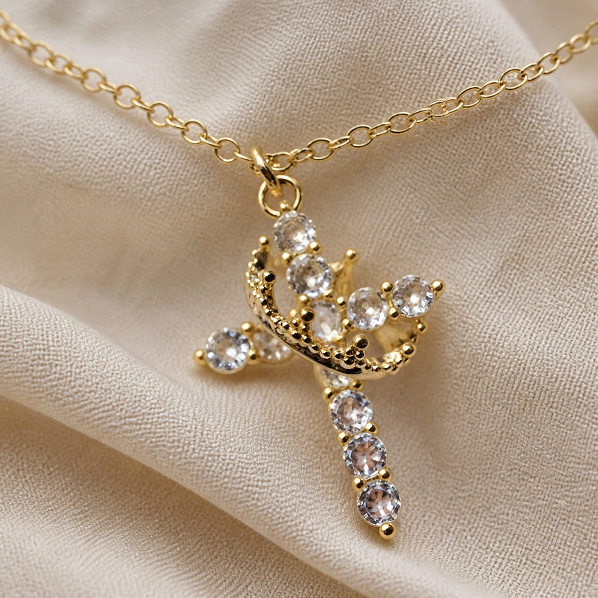 Close view of gold-color crown cross pendant and clear stones
