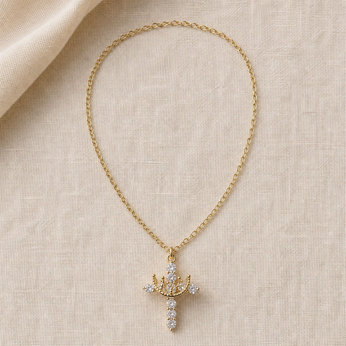 Full crown cross pendant necklace laid flat on ivory linen