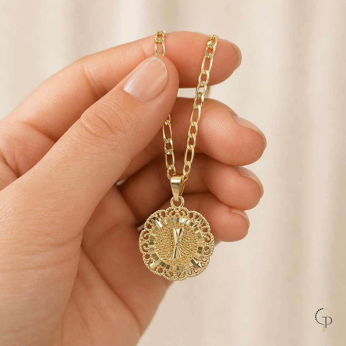 Hand holding the gold-color filigree medallion necklace to show visual scale