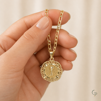 Hand holding the gold-color filigree medallion necklace to show visual scale