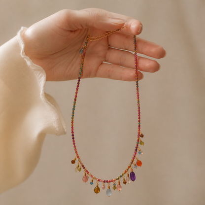 Multicolor beaded charm necklace held in one hand to show scale