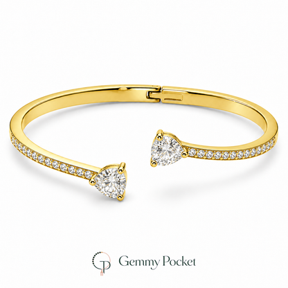 Asymmetric gold-color double-heart open bangle on a white studio background