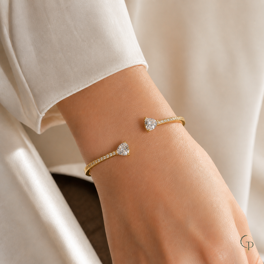 Asymmetric double-heart open bangle worn on an anonymous wrist