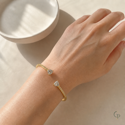 Asymmetric double-heart bangle worn on an anonymous hand and wrist