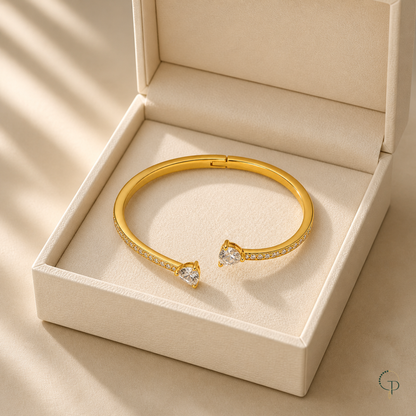 Asymmetric double-heart open bangle displayed in an unbranded ivory box
