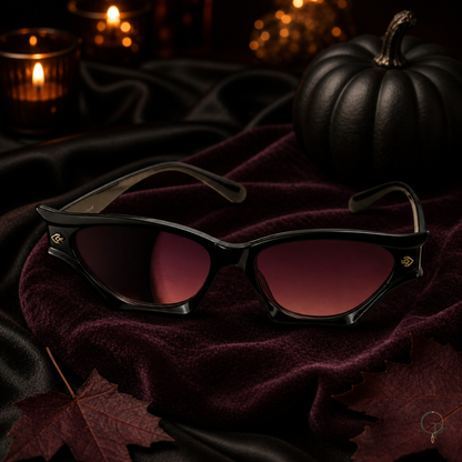 Halloween black cat-eye sunglasses on black satin with candlelight and a dark decorative pumpkin