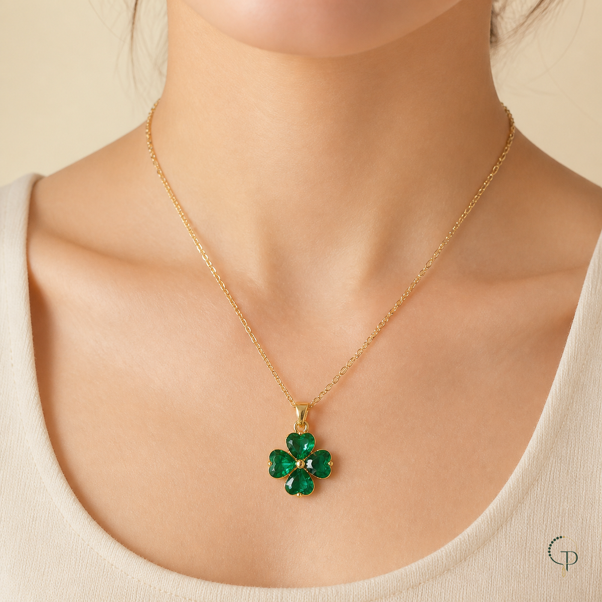 Emerald green four-leaf clover pendant necklace worn with a cream neckline