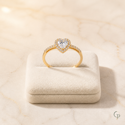 Gold-color heart halo ring displayed on an ivory jewelry cushion