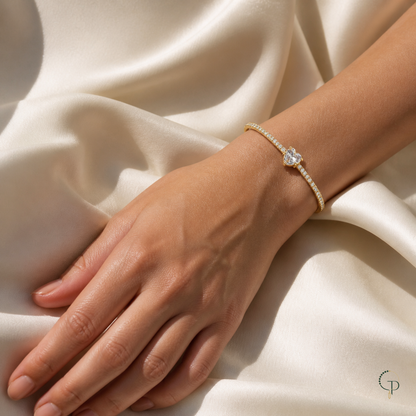 Gold-color heart cuff bracelet styled on a relaxed wrist and hand over ivory fabric.