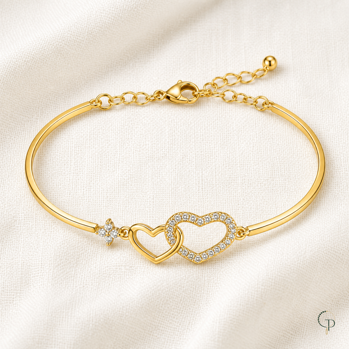 Complete gold-color two-heart bracelet arranged on ivory linen