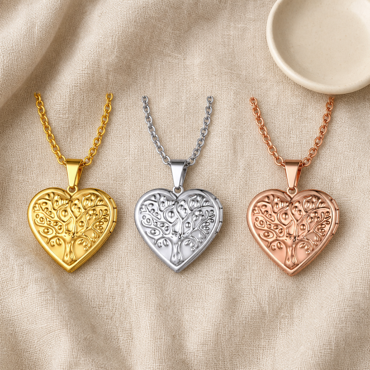 Three tree of life heart lockets beside an ivory ceramic dish