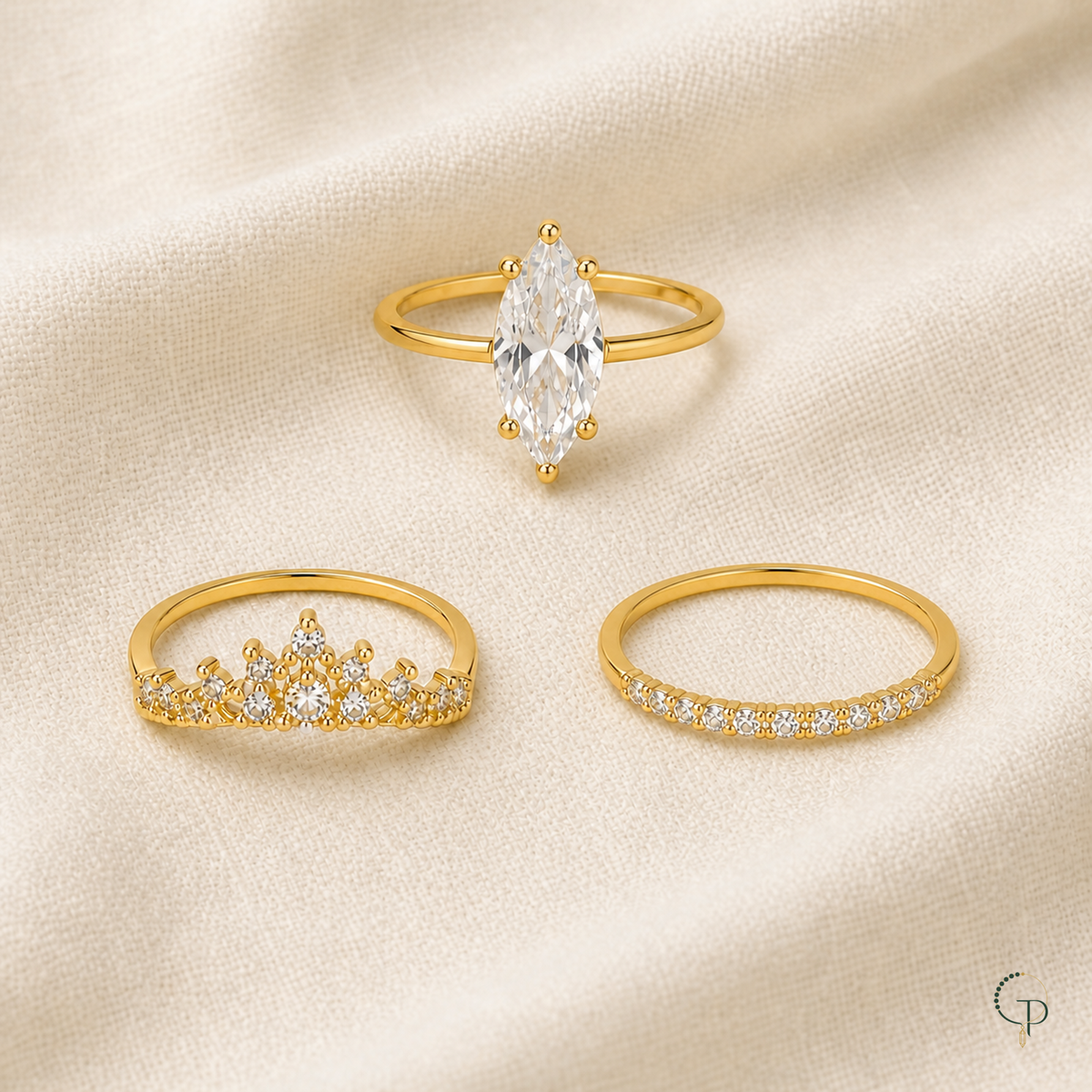 Three separate complete gold-color stacking rings arranged on warm ivory linen
