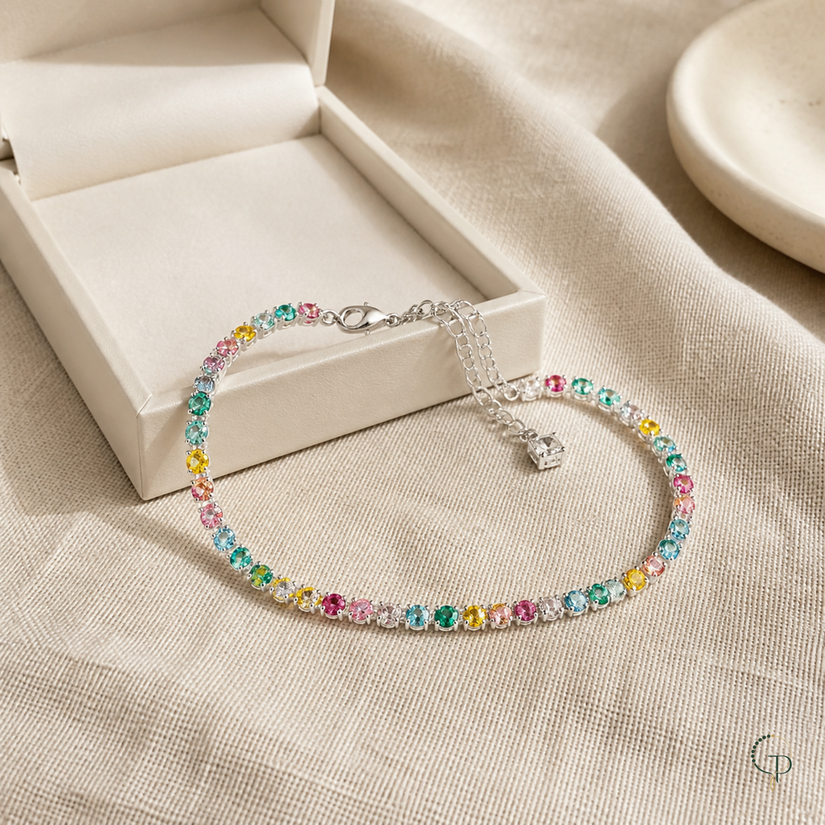 Multicolor tennis bracelet styled beside an unbranded ivory jewelry box