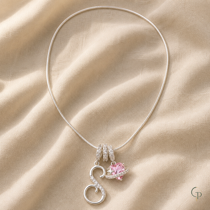 Silver-color S charm and pink planet charm necklace on warm oatmeal linen