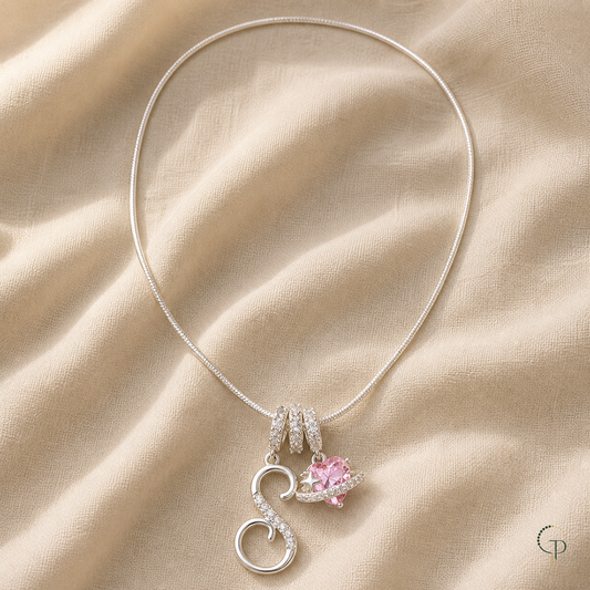 Silver-color S charm and pink planet charm necklace on warm oatmeal linen
