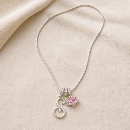 Full dual-charm snake chain necklace laid flat on ivory linen