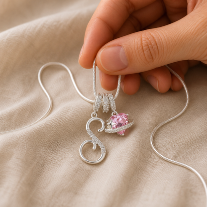 Hand holding the S and pink planet charms for visual scale