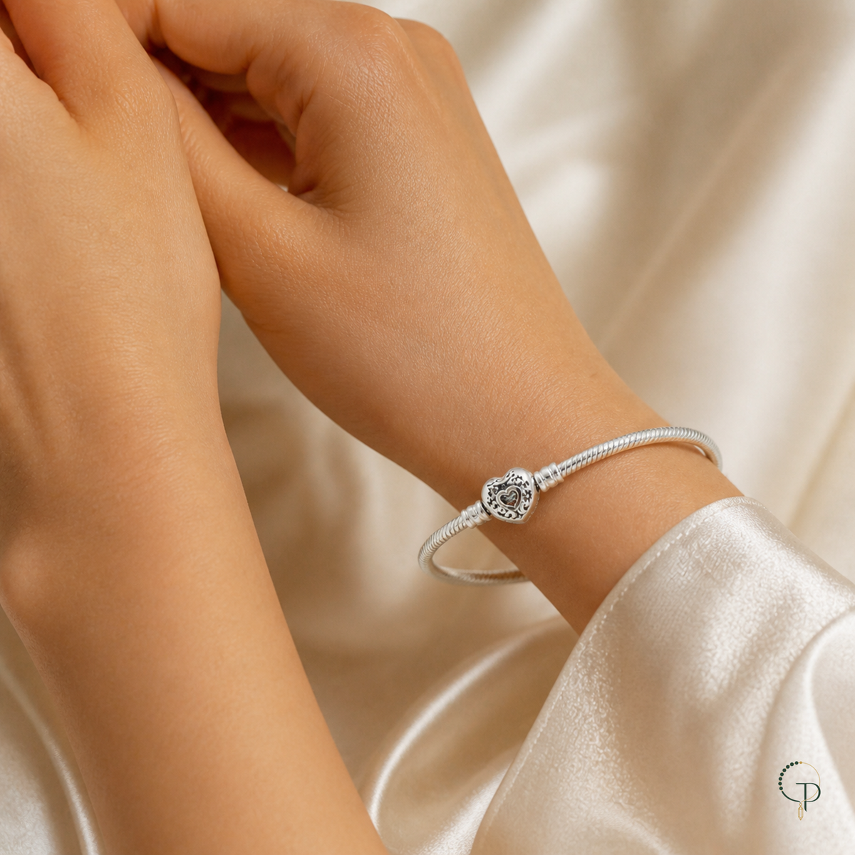 Openwork heart clasp snake-chain bracelet worn around an anonymous wrist