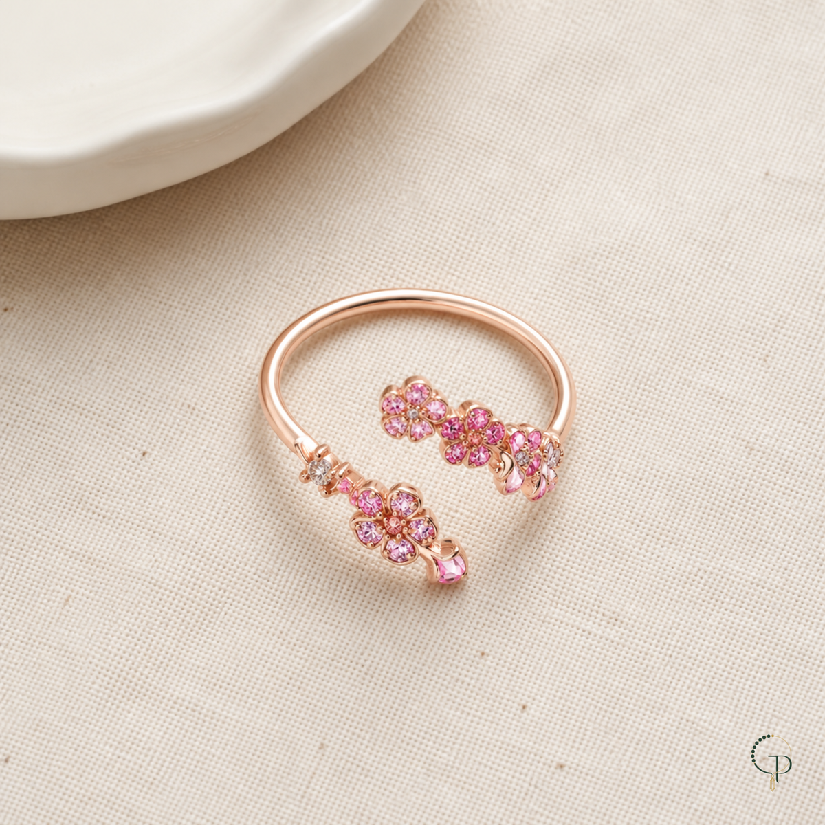 Complete rose-gold-color pink blossom bypass ring arranged on oatmeal linen