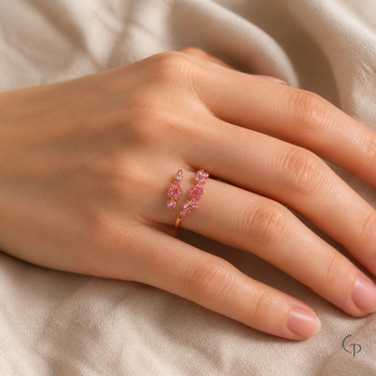 Pink blossom bypass ring worn at natural scale on a hand over cream linen