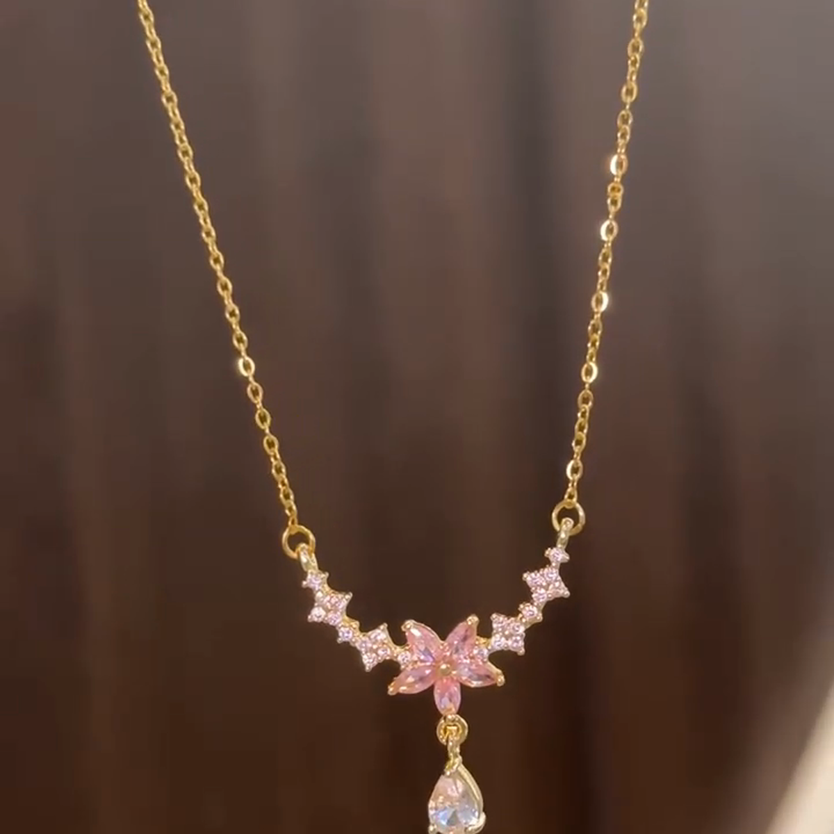 Front view of the pink blossom necklace and dangling clear drop