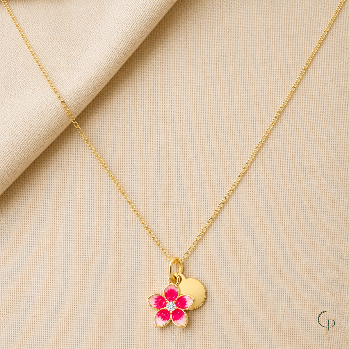 Pink blossom and disc pendant necklace arranged on warm oatmeal linen
