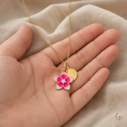 Pink five-petal blossom pendant and gold-color chain displayed across an open palm