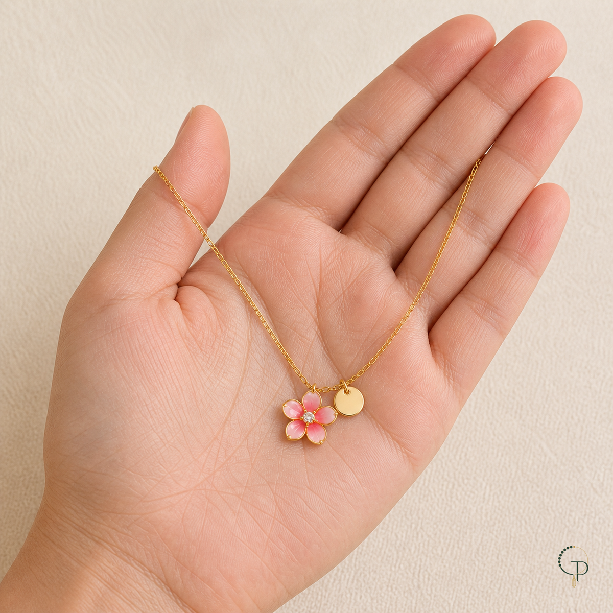 Pink blossom pendant necklace displayed across an open palm for scale