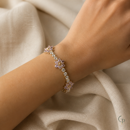 Gold-color bracelet with pink blossom motifs worn on a wrist