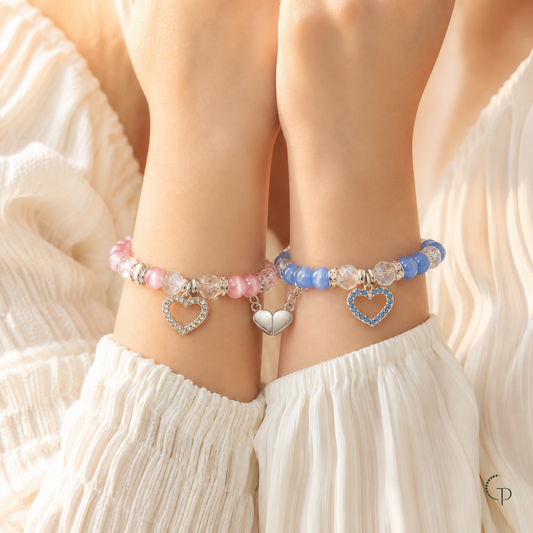 Two friends wearing pink and blue matching bracelets with magnetic heart connected