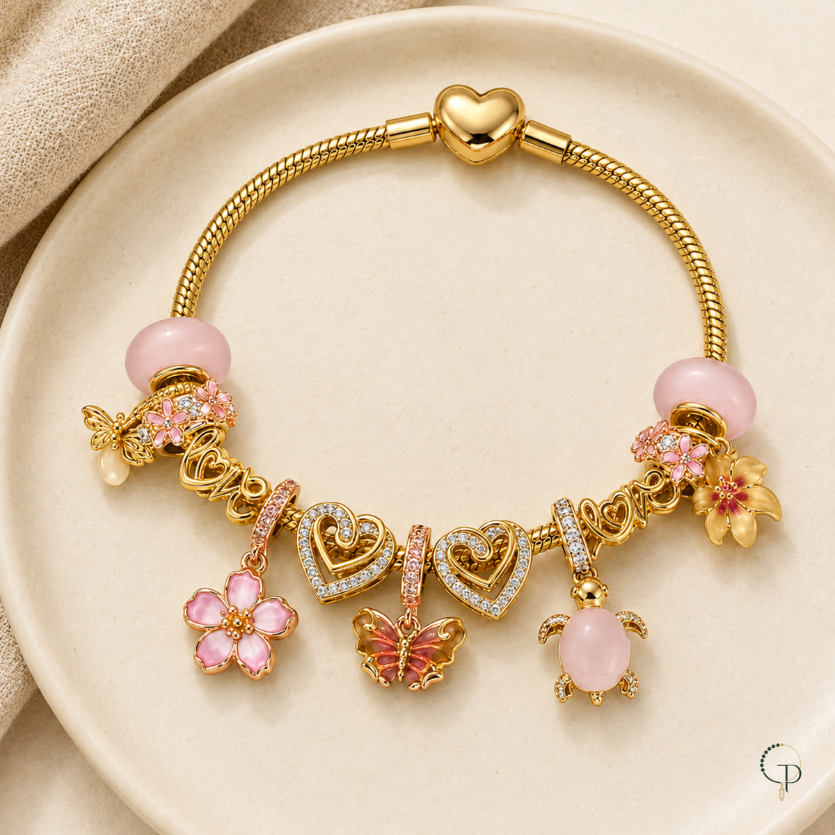 Complete pink and gold-color charm bracelet arranged on an ivory ceramic dish