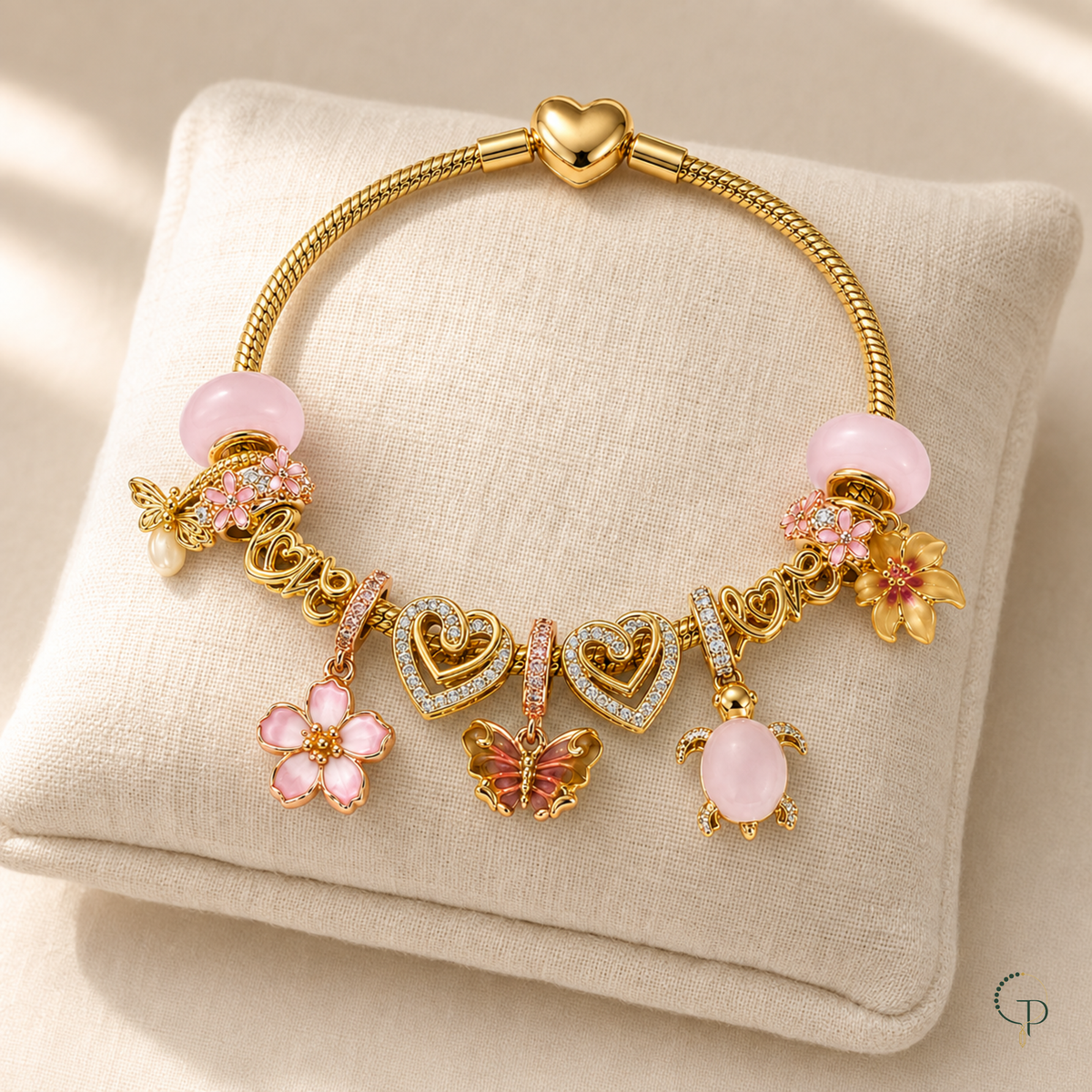 Pink and gold-color charm bracelet displayed on an ivory linen cushion