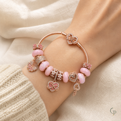 Pink infinity charm bracelet worn on a wrist beside a cream knit cuff