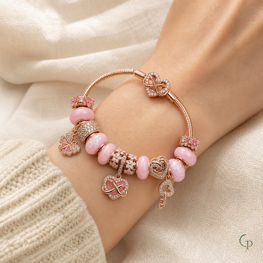 Pink infinity charm bracelet worn on a wrist beside a cream knit cuff
