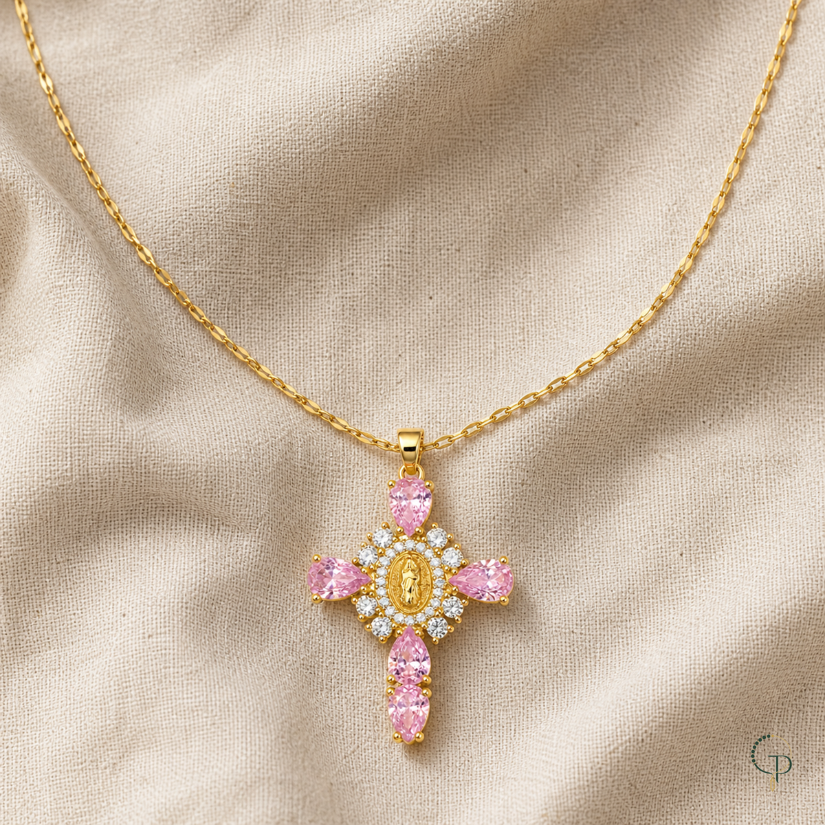 Pink teardrop halo pendant and gold-color chain draped on oatmeal linen